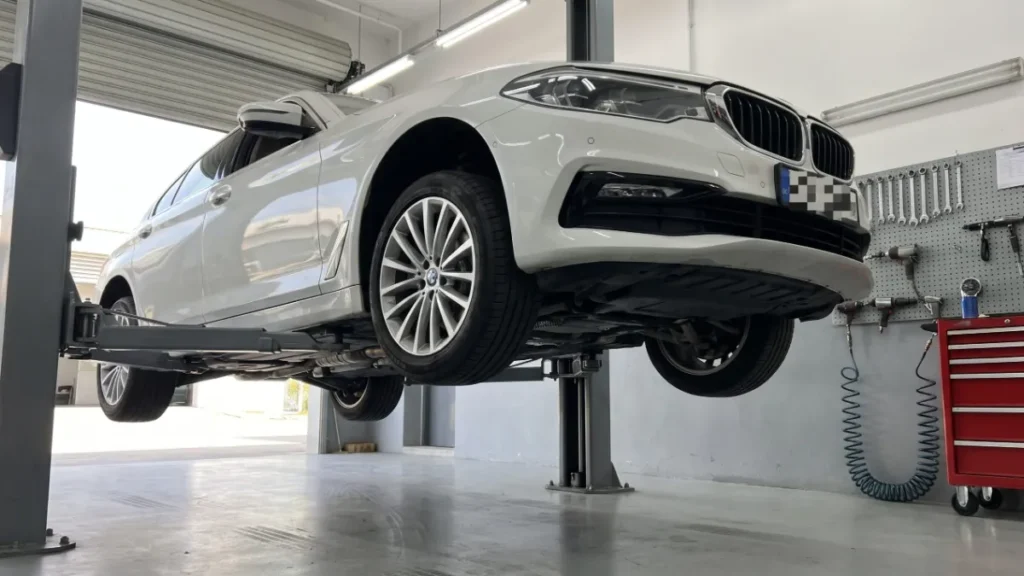 정비 리프트에 올린 흰색 BMW 5시리즈